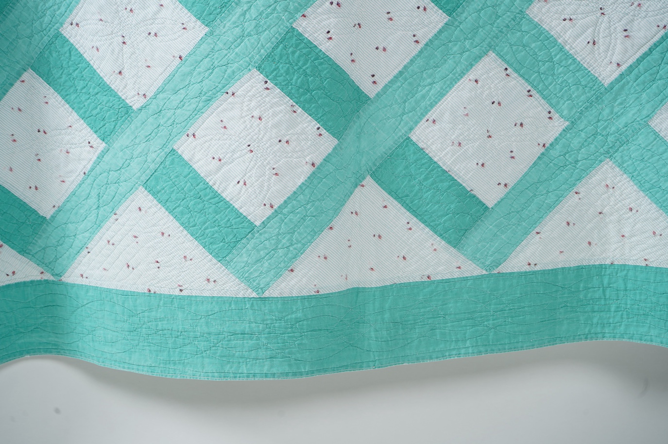 A late 19th early 20th century English, Durham, immaculately hand quilted bedcover. Designed using a plain mint green cotton and a complimentary light floral cotton stripe, in an all over lattice design, with a mint gree